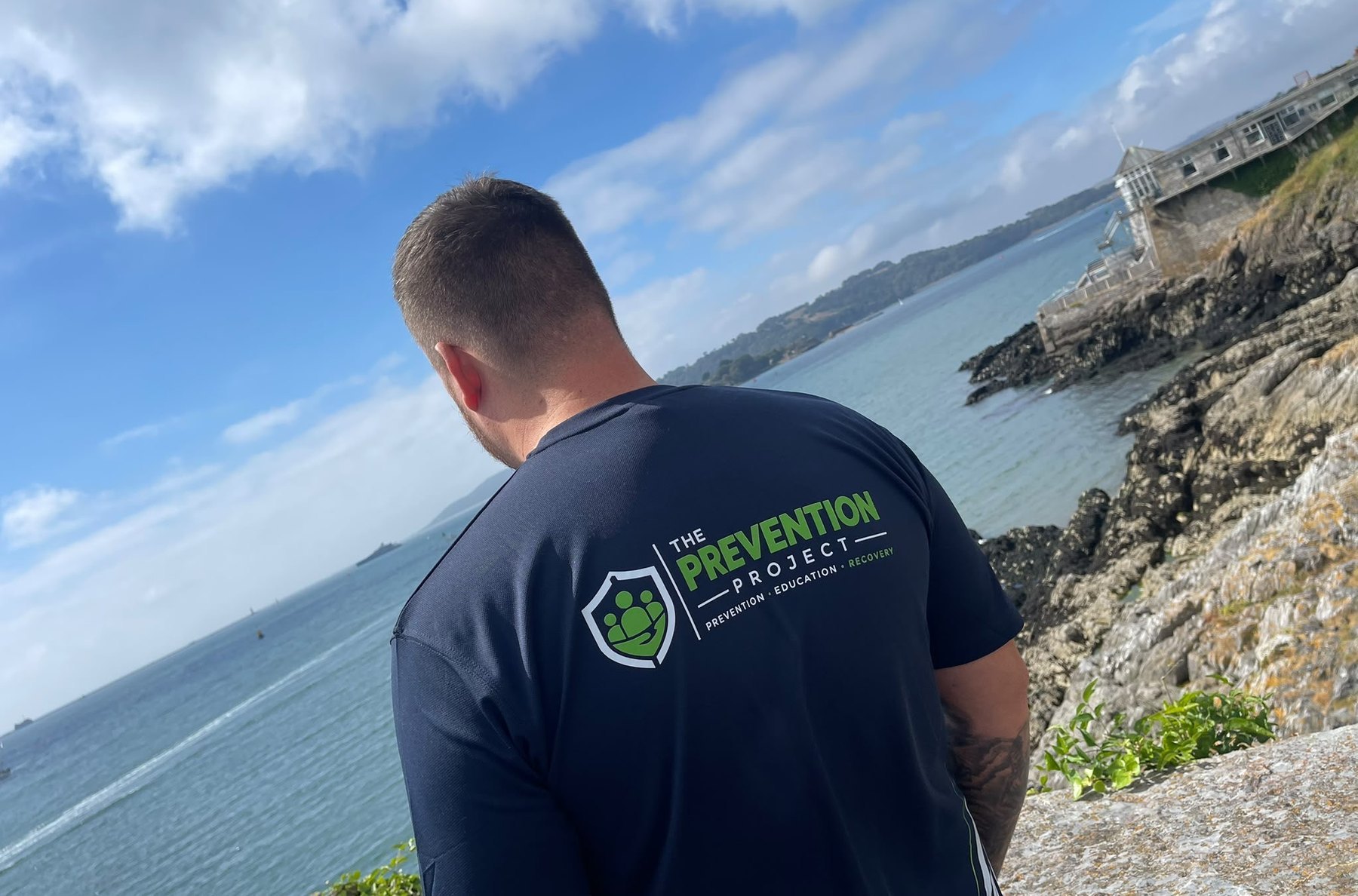 Macauley South looking out over the water, wearing a The Prevention Project shirt